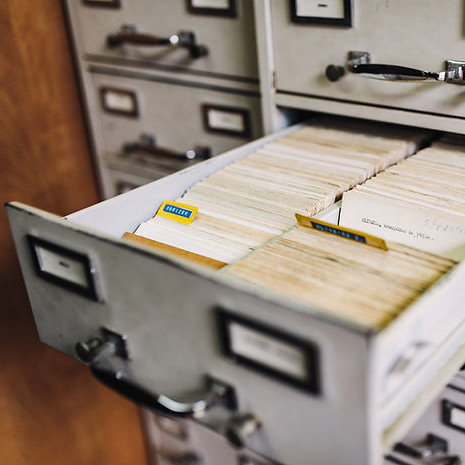 An open filing cabinet filled with documents to be archived.